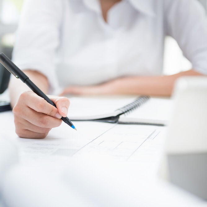 Close up to Hand of women to architect sketch for Interior designer works in construction project on desk modern in white office.Technology interior design. Job of interior designer concept.